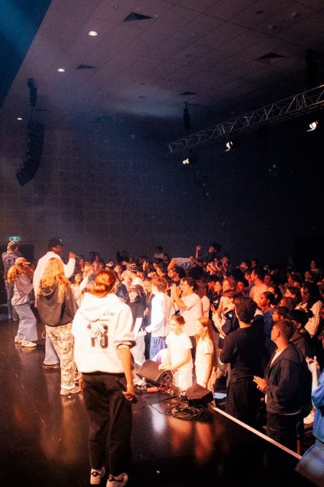 A crowd of young people watch performers on stage