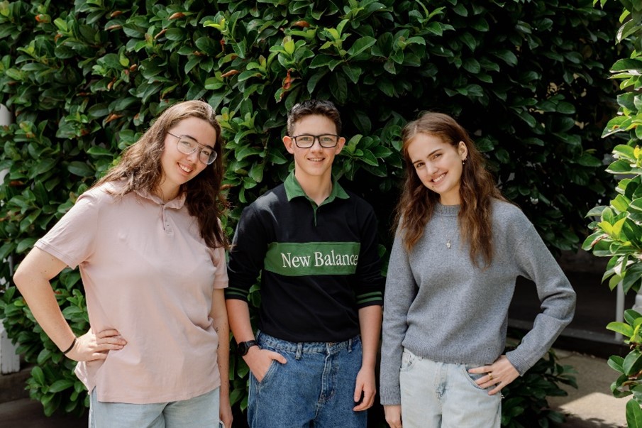 A group of young people stand in front of a tree smiling