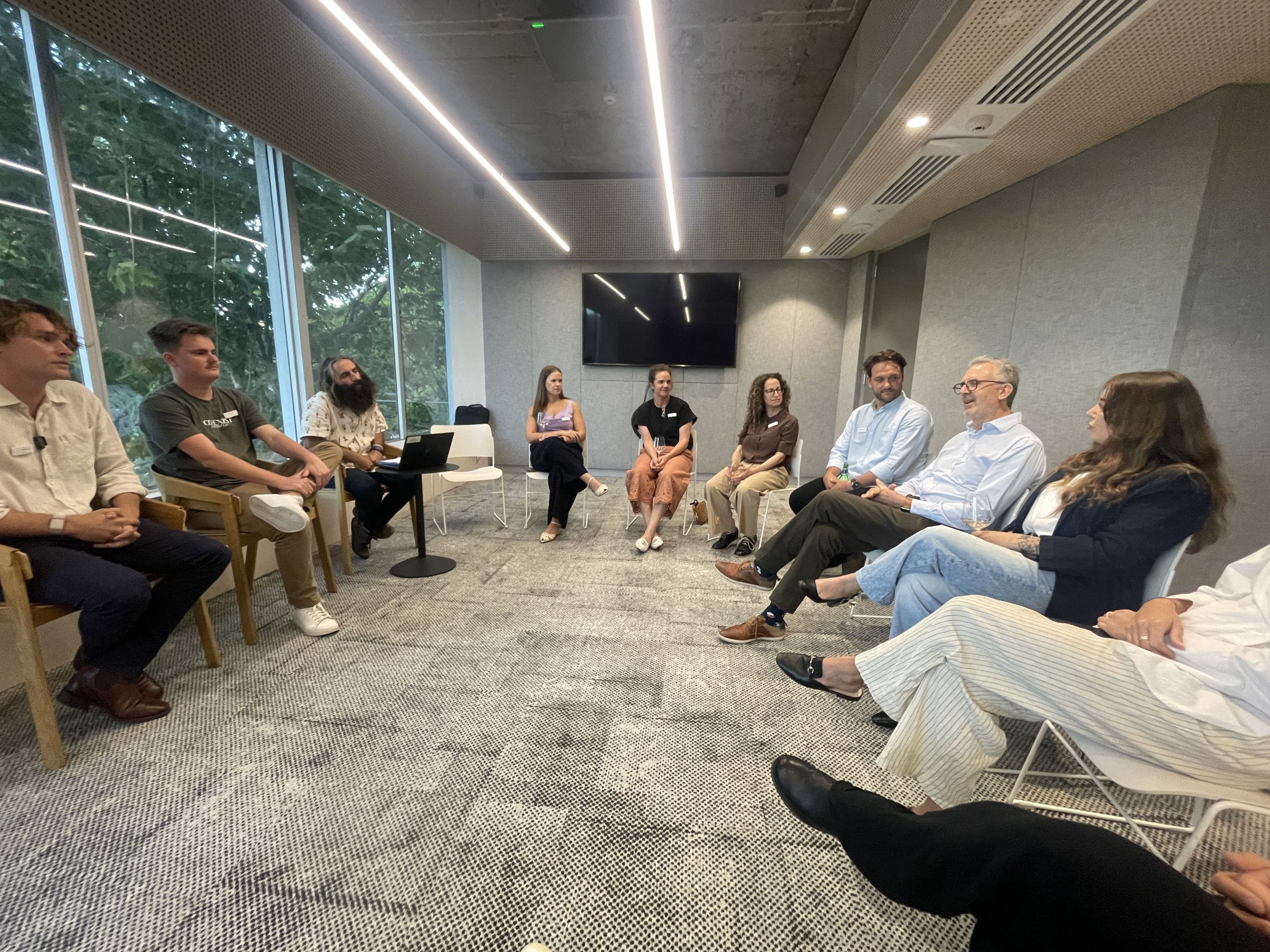A group of people sitting in a circle in a meeting room listening