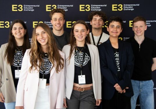 A group of Young People gathered in front of signage at a conference